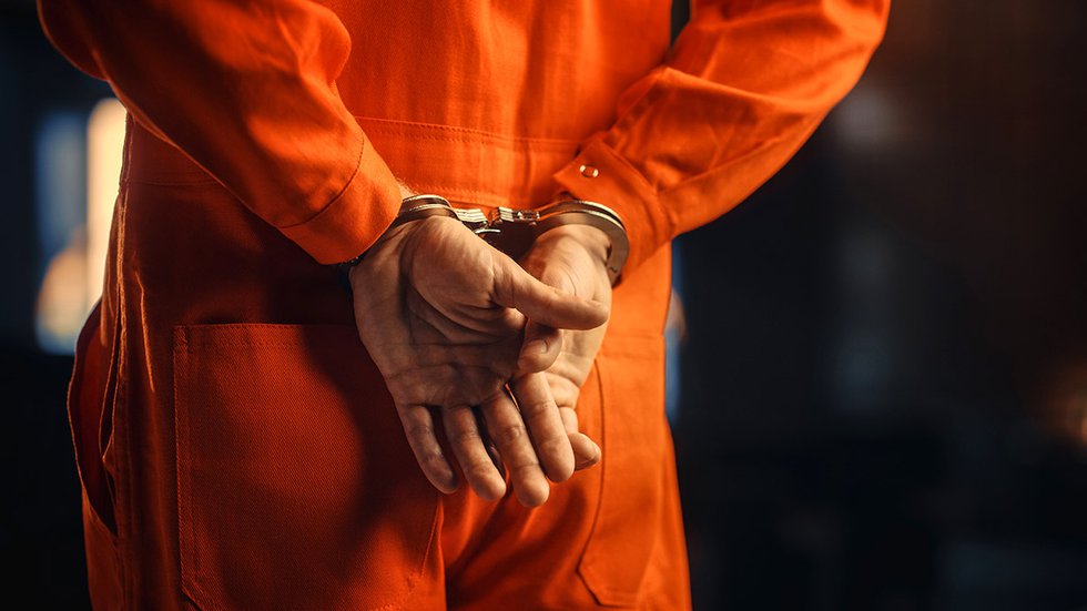 Handcuffed defendant in orange jumpsuit
