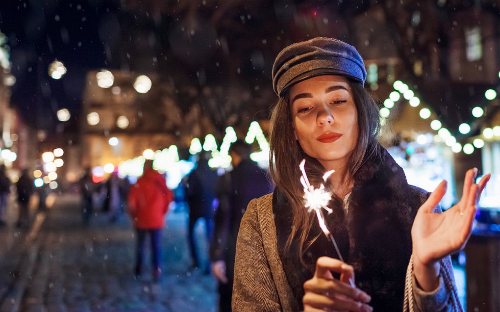 Woman burning sparkler at city street fair